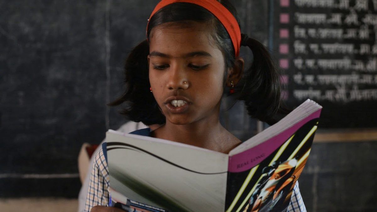A young student reading aloud from her textbook in a rural classroom in Mulshi Taluka.