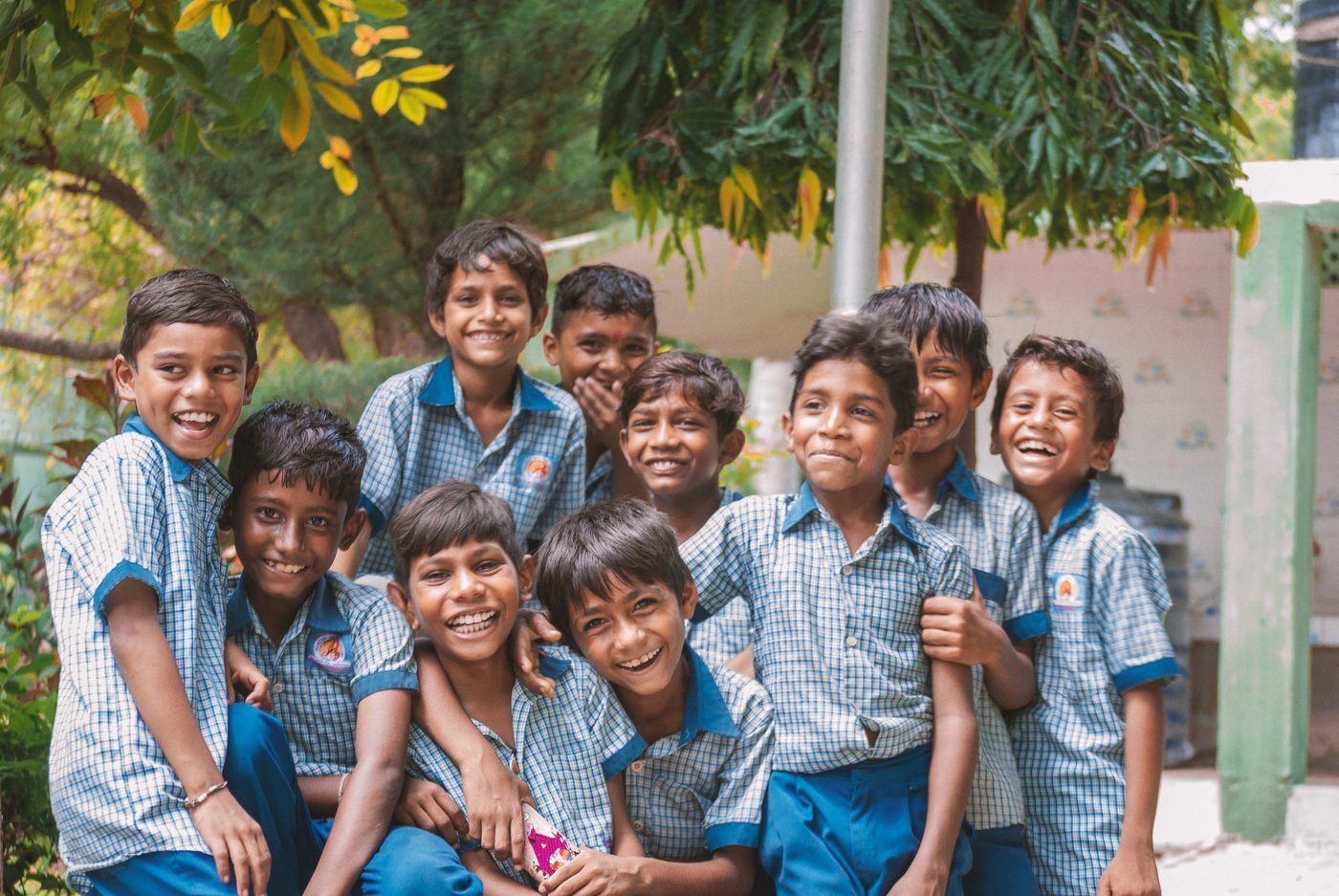 A group of schoolboys in uniform laughing together outdoors.